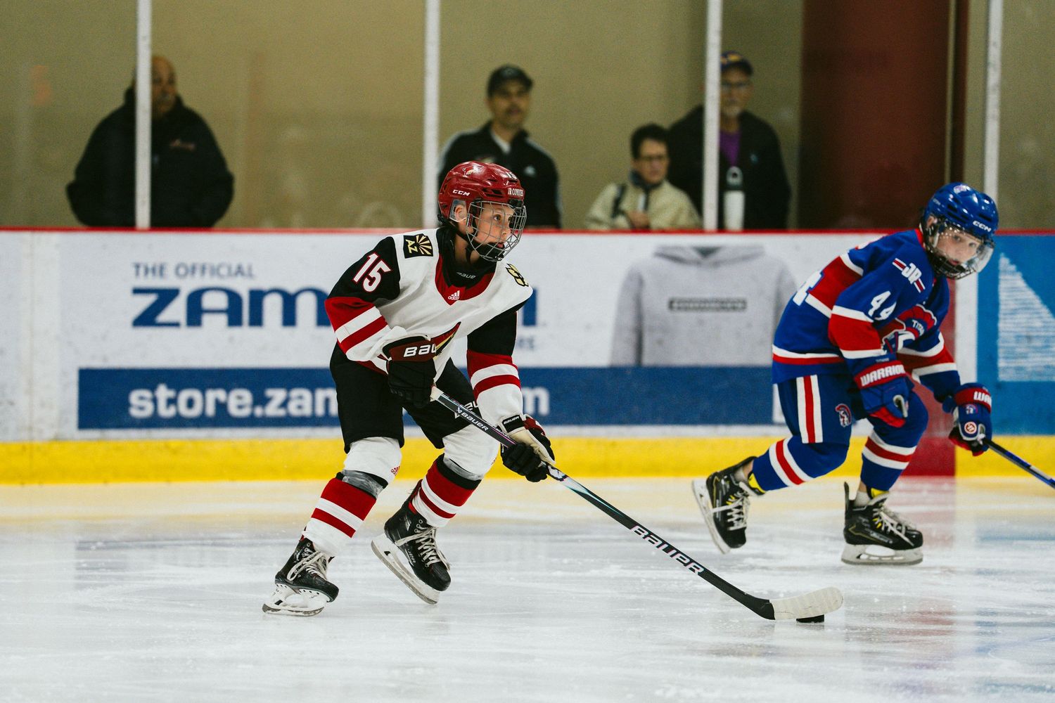 Ice hockey players compete during an intense game with players skating and handling the puck on the rink.