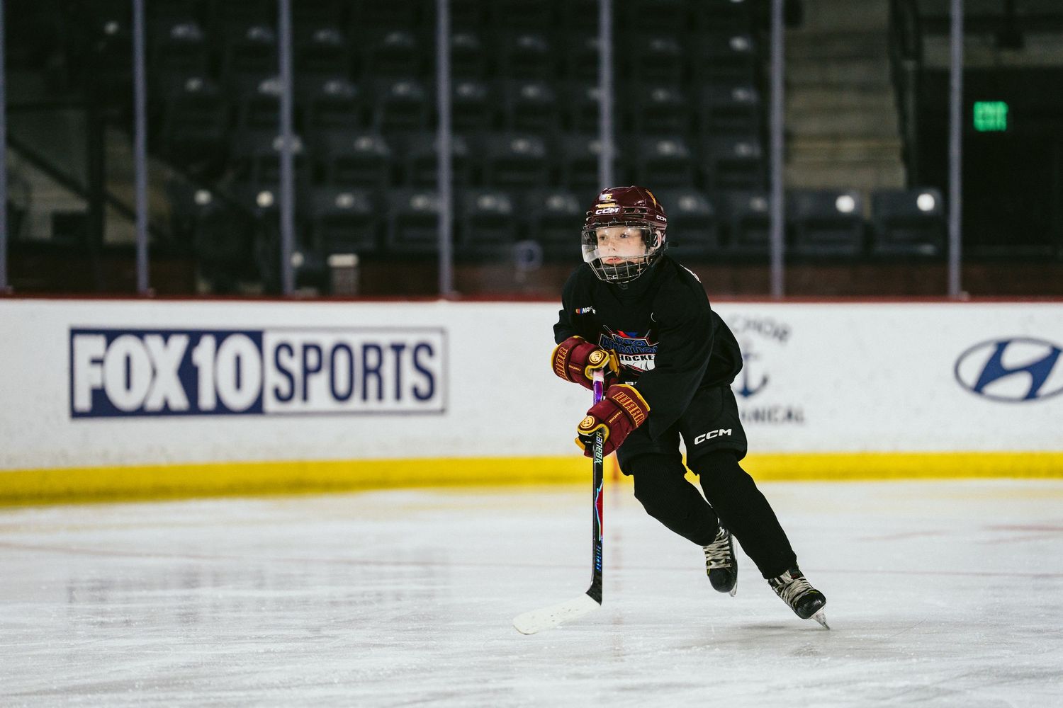 A young youth hockey player skates across an indoor ice rink during a hockey practice session.