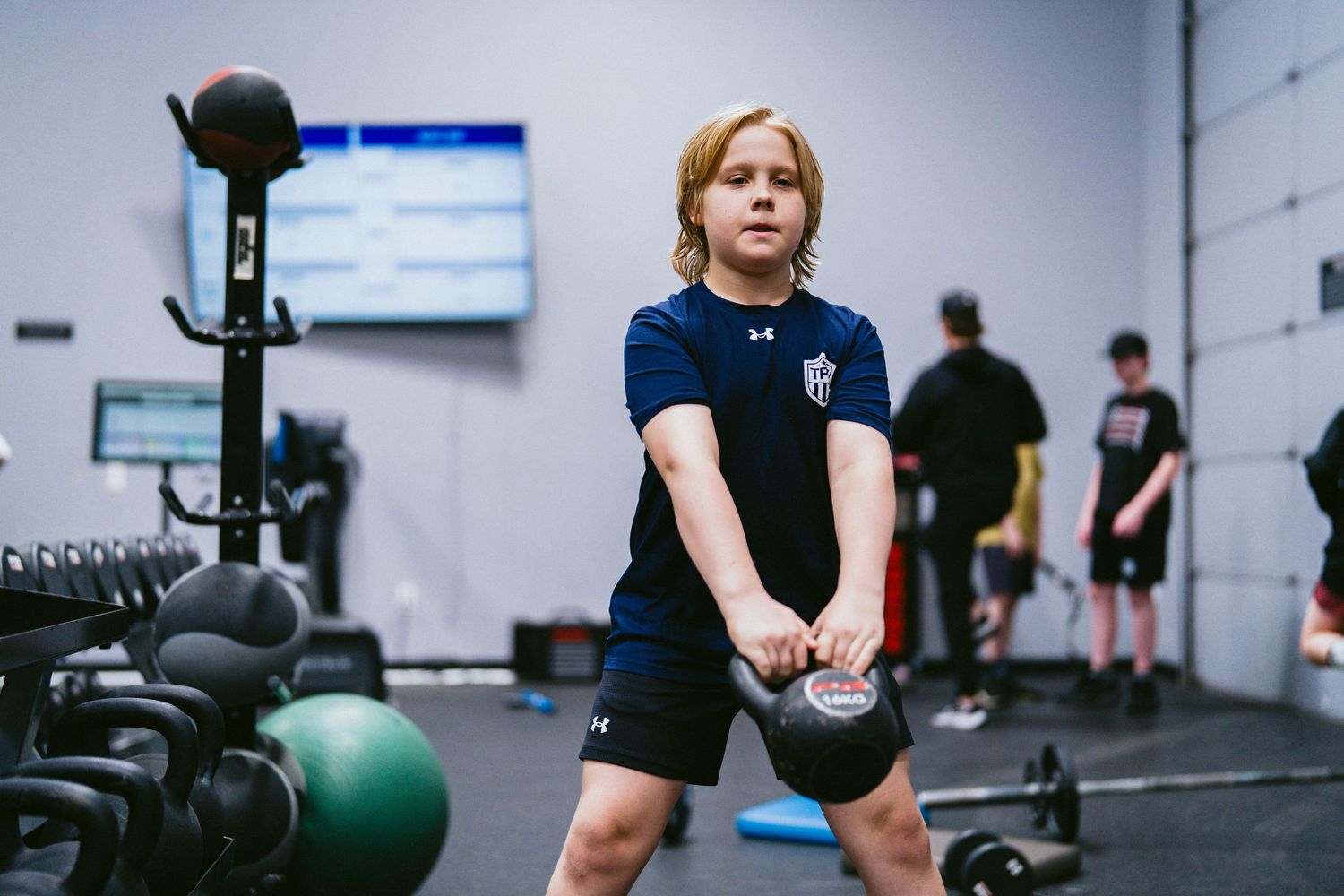 Young athlete performing a kettlebell exercise during a youth strength training session.