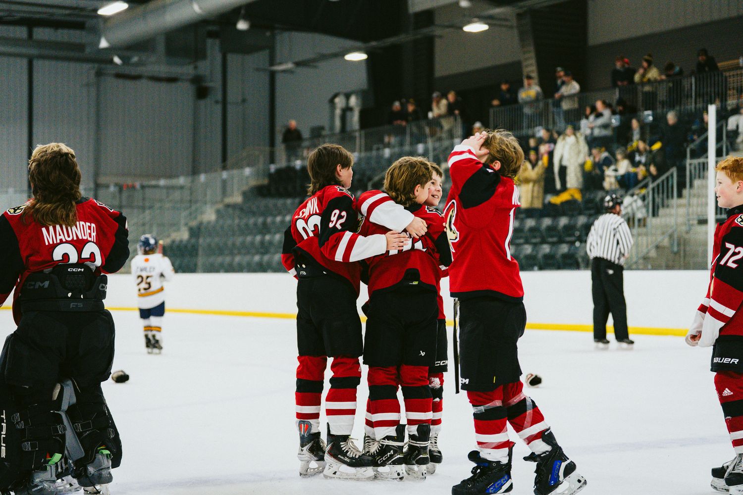 Wide view of hockey players spread across an indoor ice rink during practice.