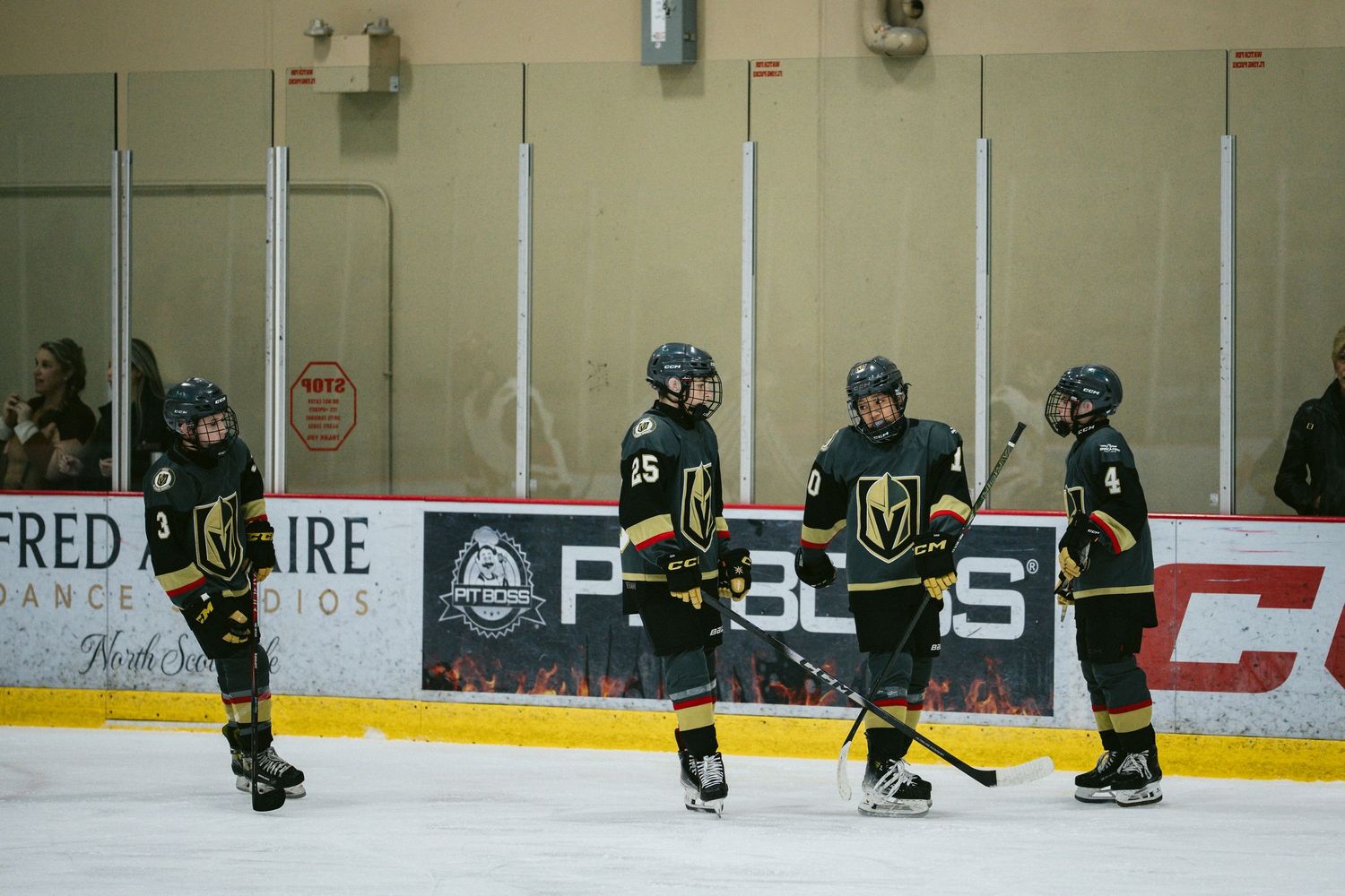 Hockey players in dark uniforms spread across the ice during practice session.