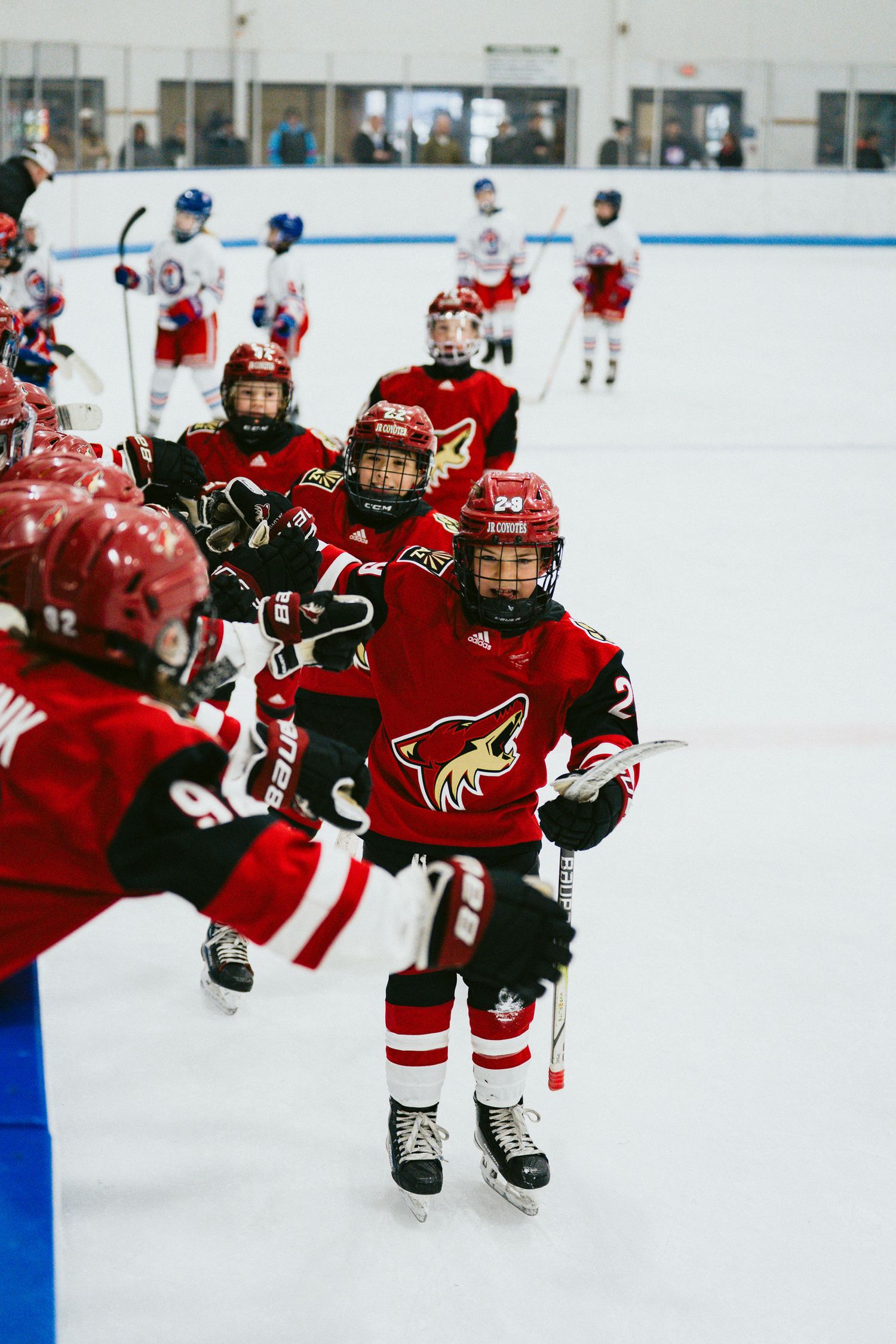 Youth hockey team in red uniforms skates together during practice on ice.