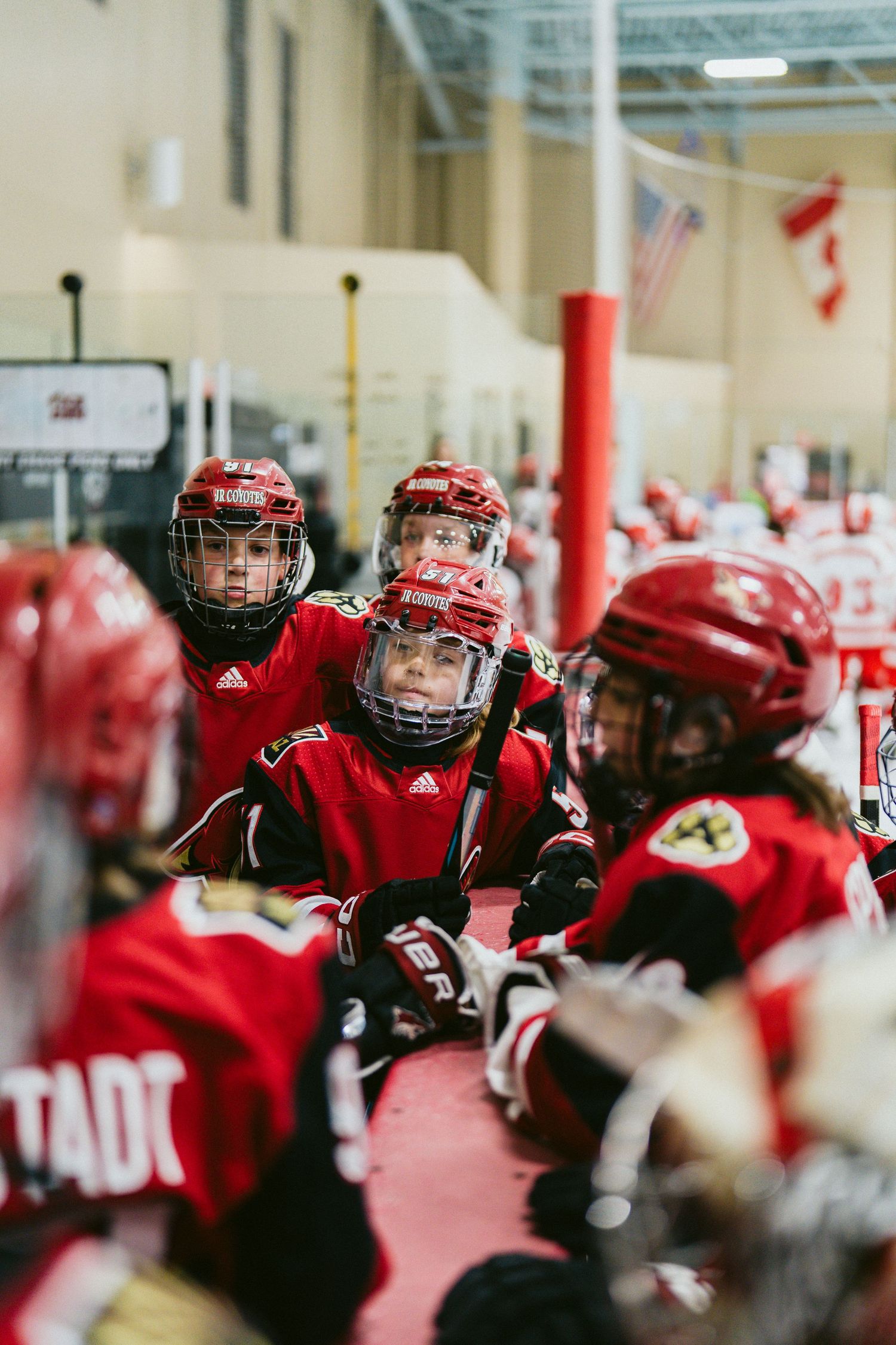 Close-up view of hockey players in red jerseys and protective gear during an indoor practice.
