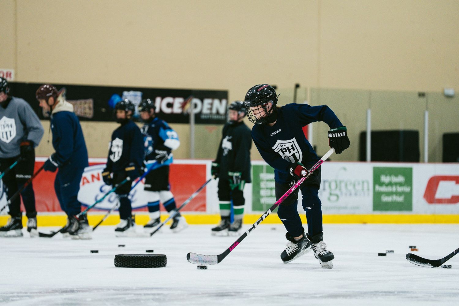 Hockey player in black jersey handles puck during indoor ice skating practice session.