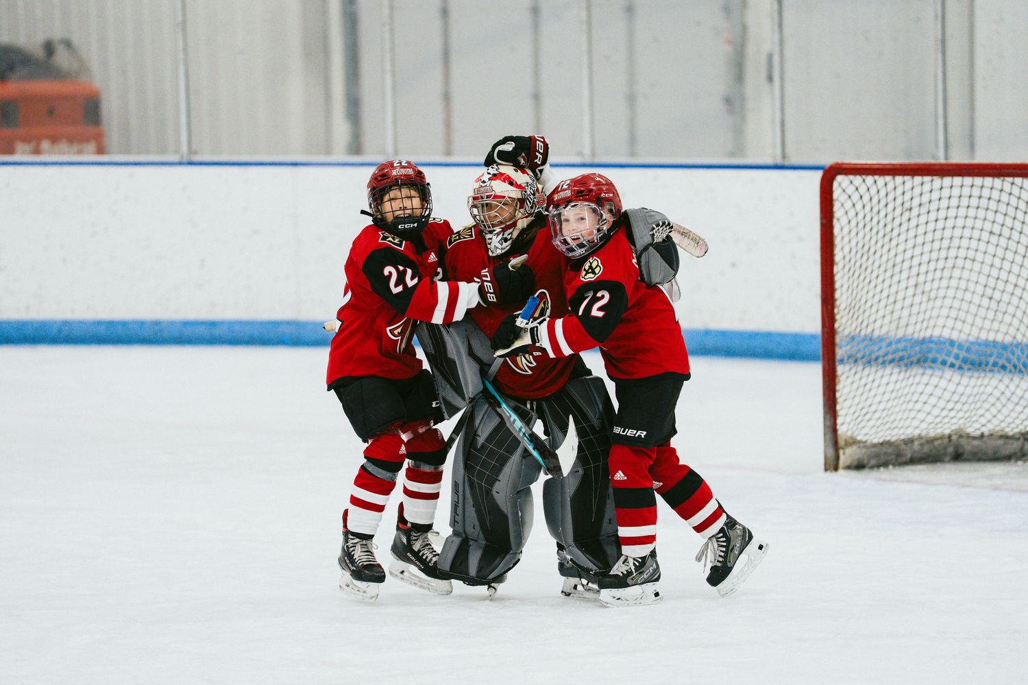 Hockey players in red uniforms gather near the bench during a match.