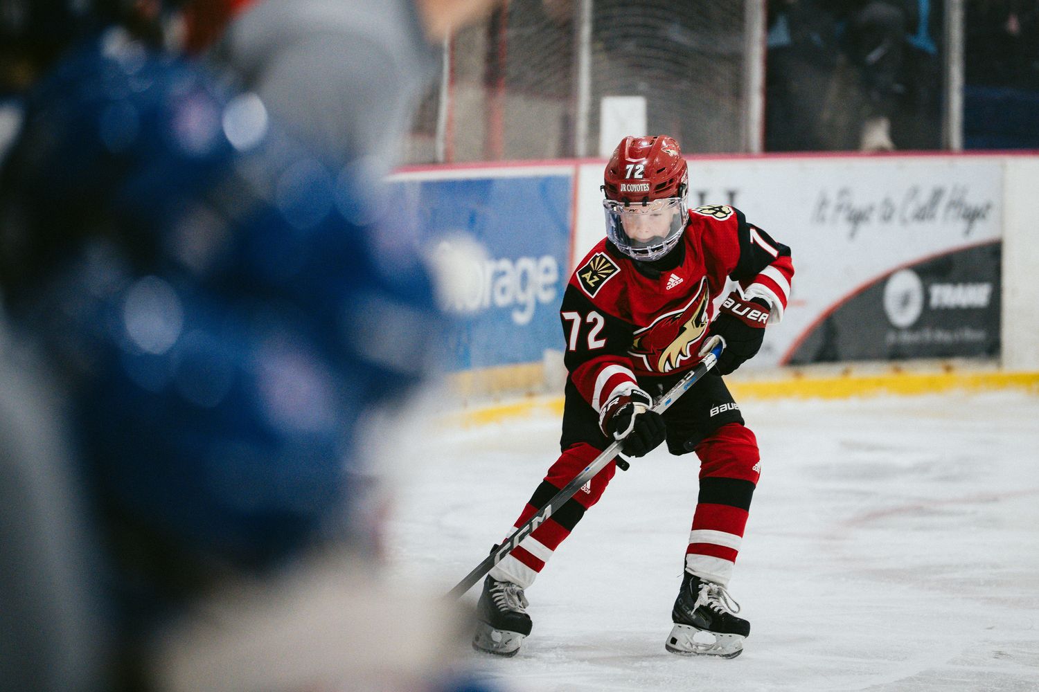 Hockey players in red and white uniforms skating during competitive match.