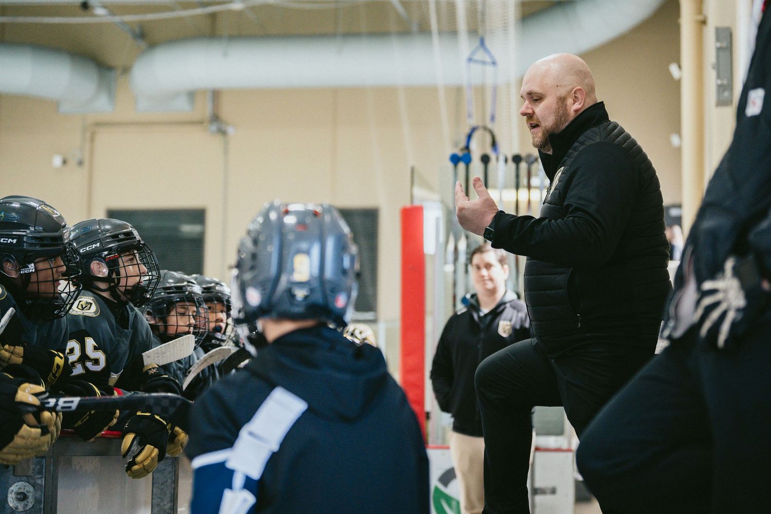 Coaches and players gathered at the bench during a hockey game.