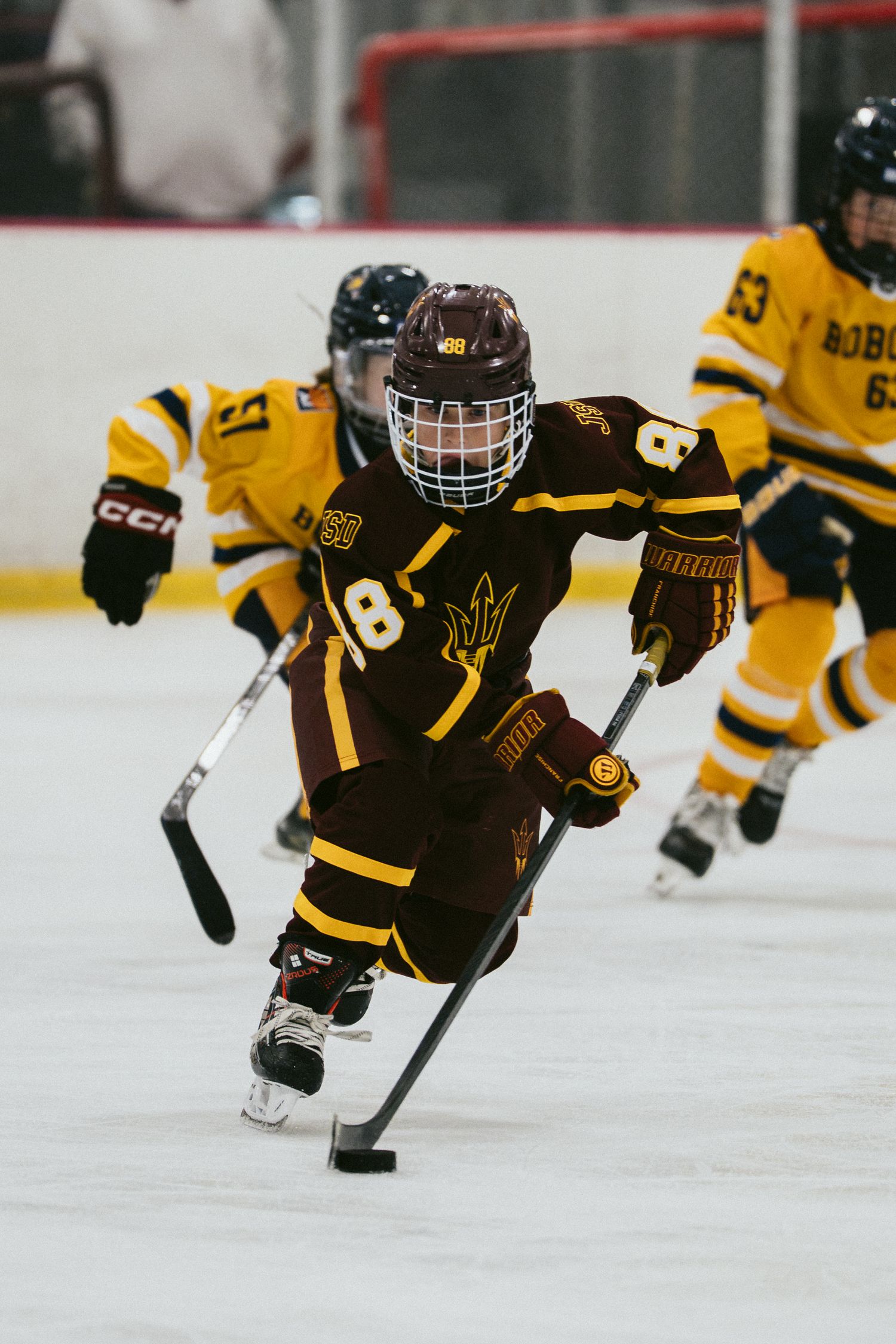 Arizona State Sun Devils hockey player number 18 skates with the puck during a competitive ice hockey game.