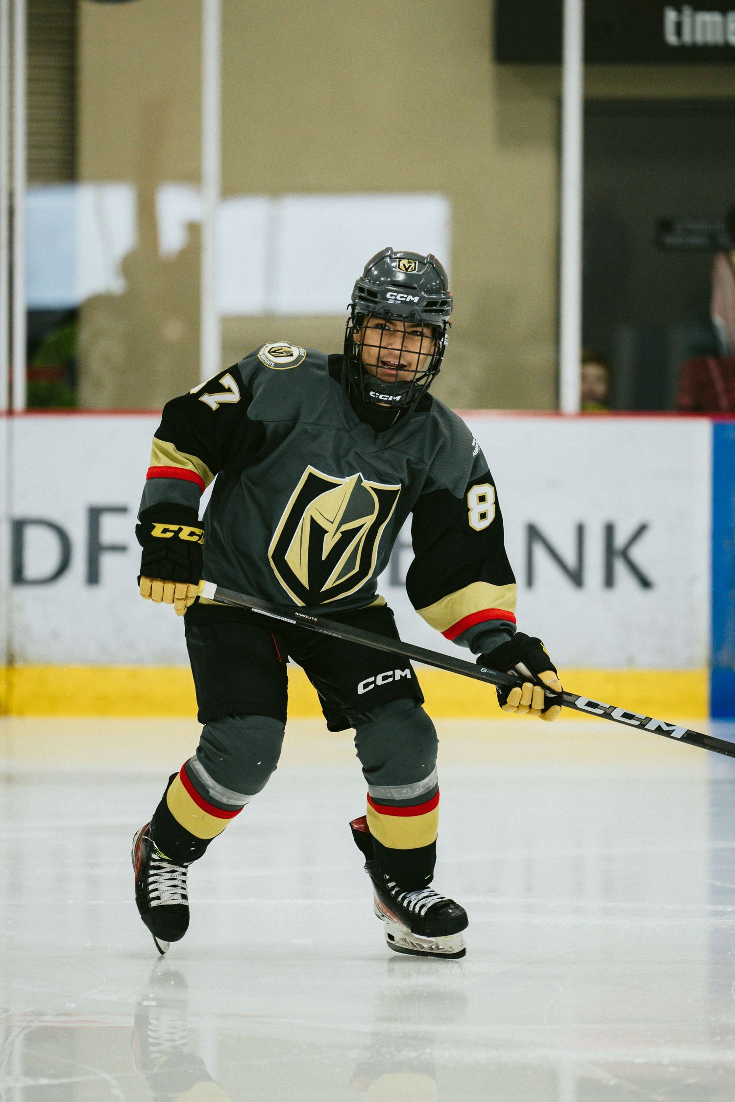 Hockey players in Vegas Golden Knights uniforms skate low across the ice during gameplay.