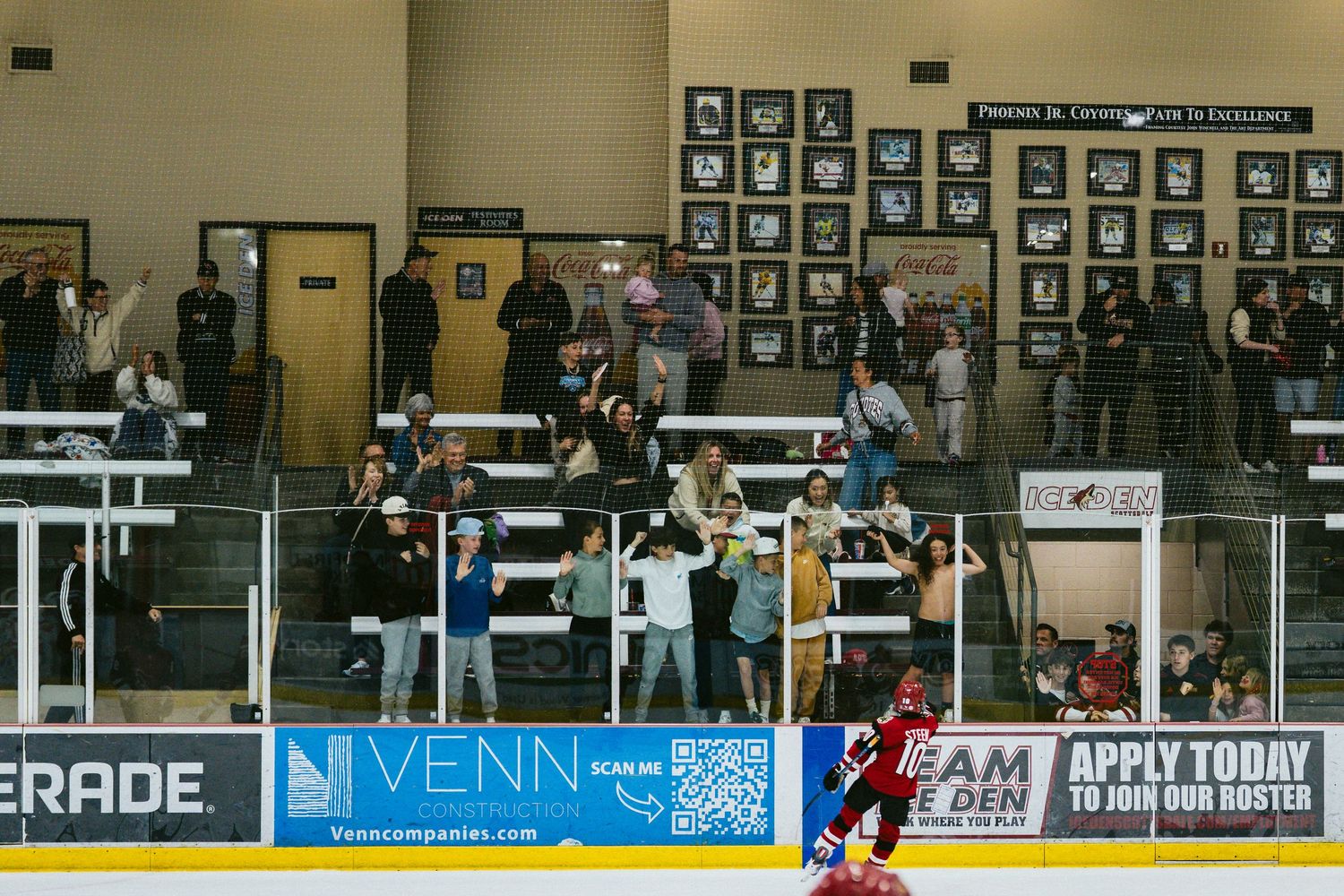 Indoor hockey rink with spectator seating and advertising banners visible along the boards.
