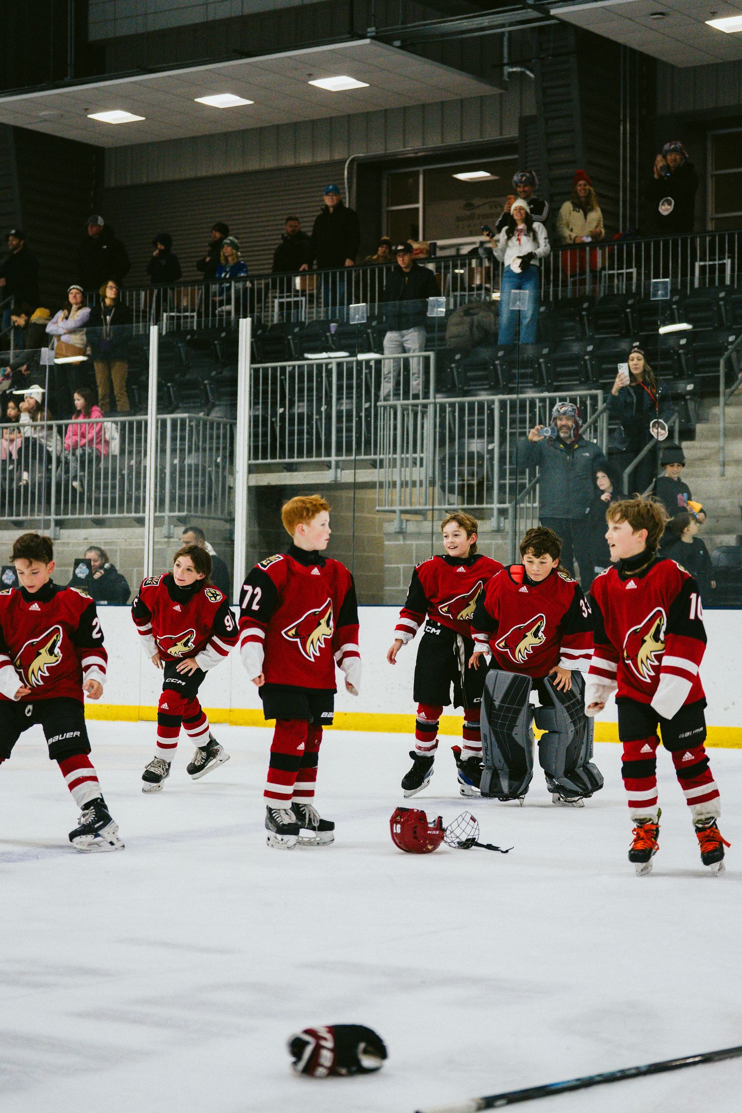 Hockey team in red uniforms performing synchronized sliding exercises on the ice rink.