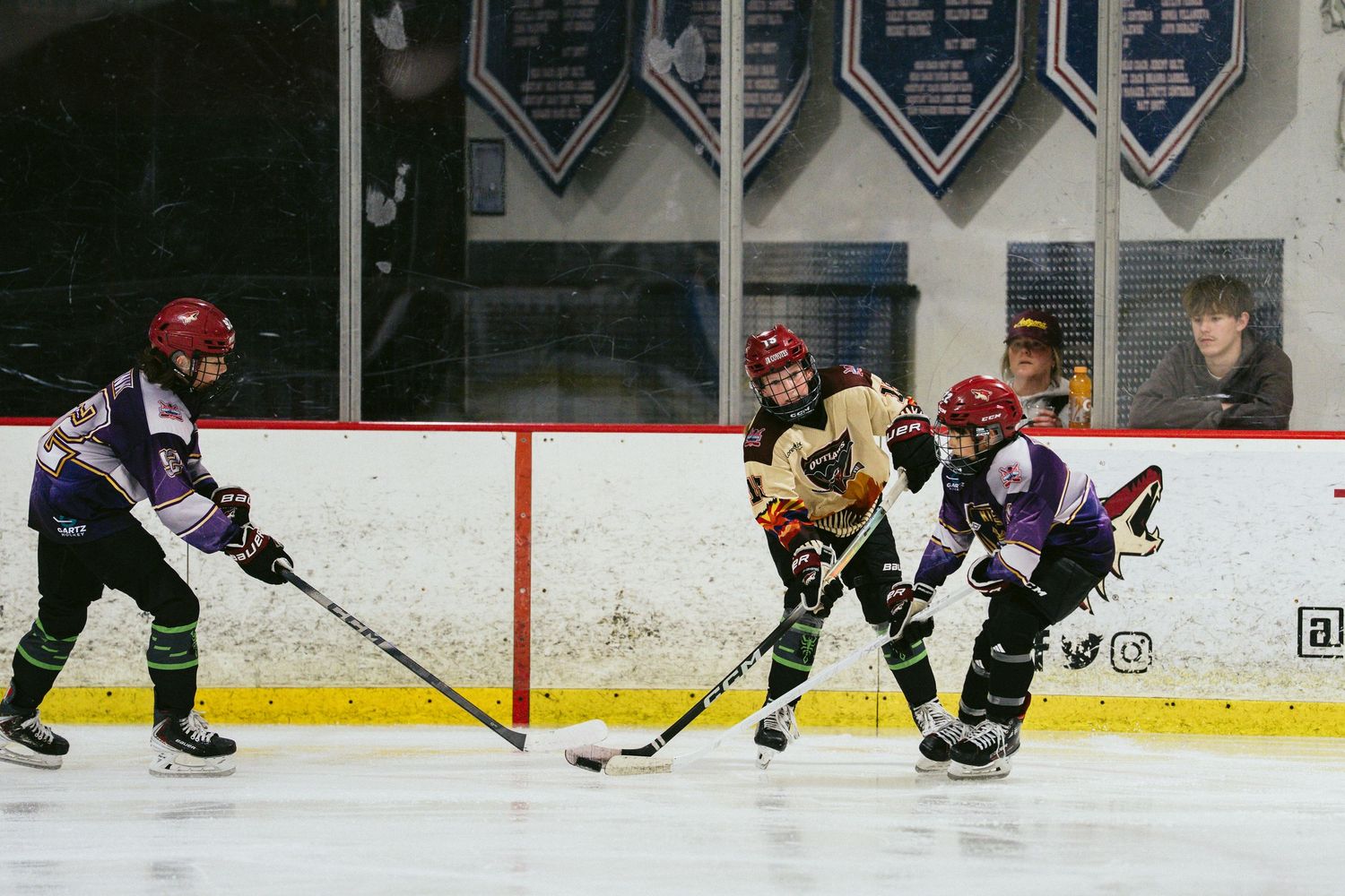 Young ice hockey players battle for the puck during a competitive youth hockey match indoors.