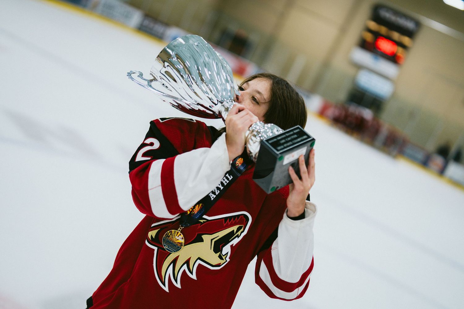 Hockey players in maroon uniforms celebrate together on the ice after scoring.