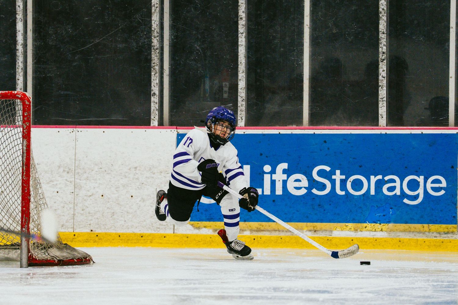 Hockey player skating towards goal during game at indoor ice arena.