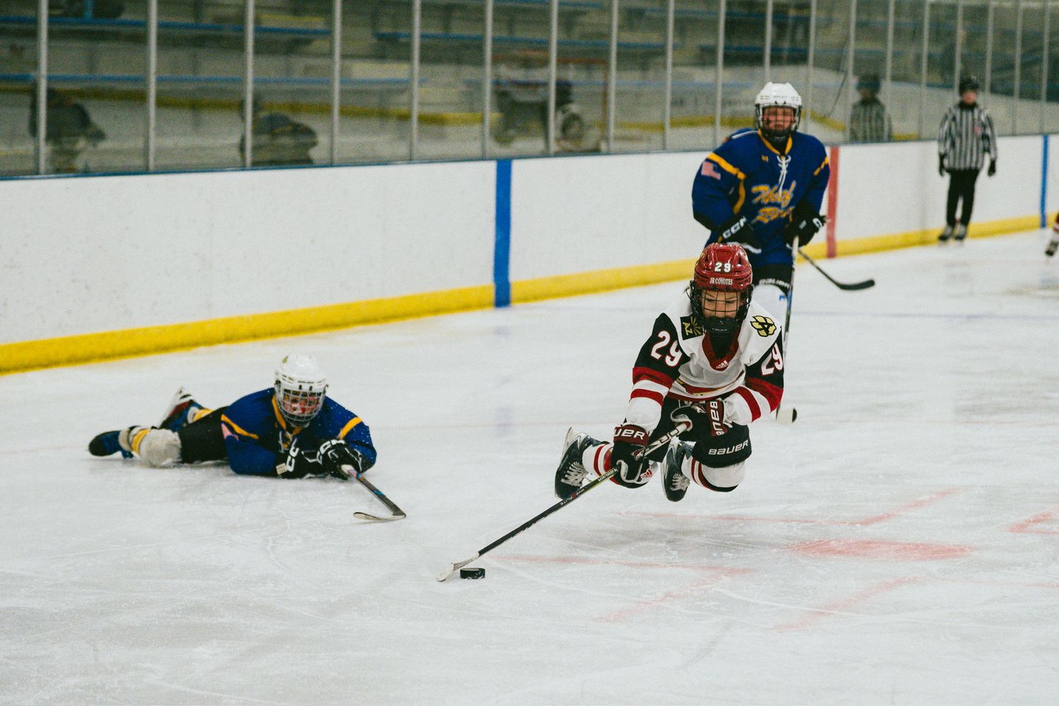 Hockey players diving and sliding on ice during competitive play.