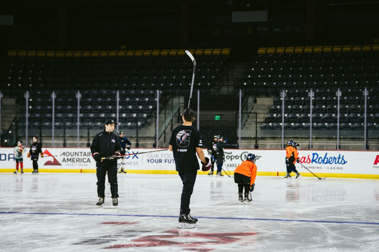 Ice hockey coach instructs young players on an indoor rink during a youth hockey practice session.