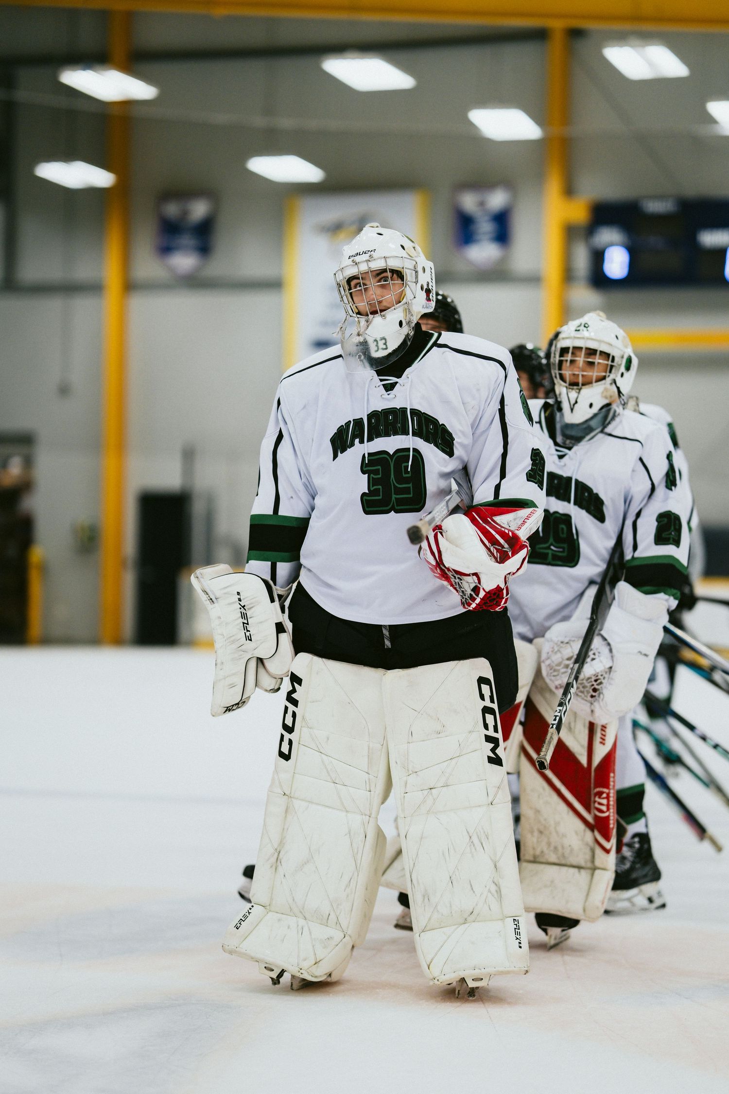 Hockey goalie in Warriors number 39 jersey stands on ice rink in full protective gear.