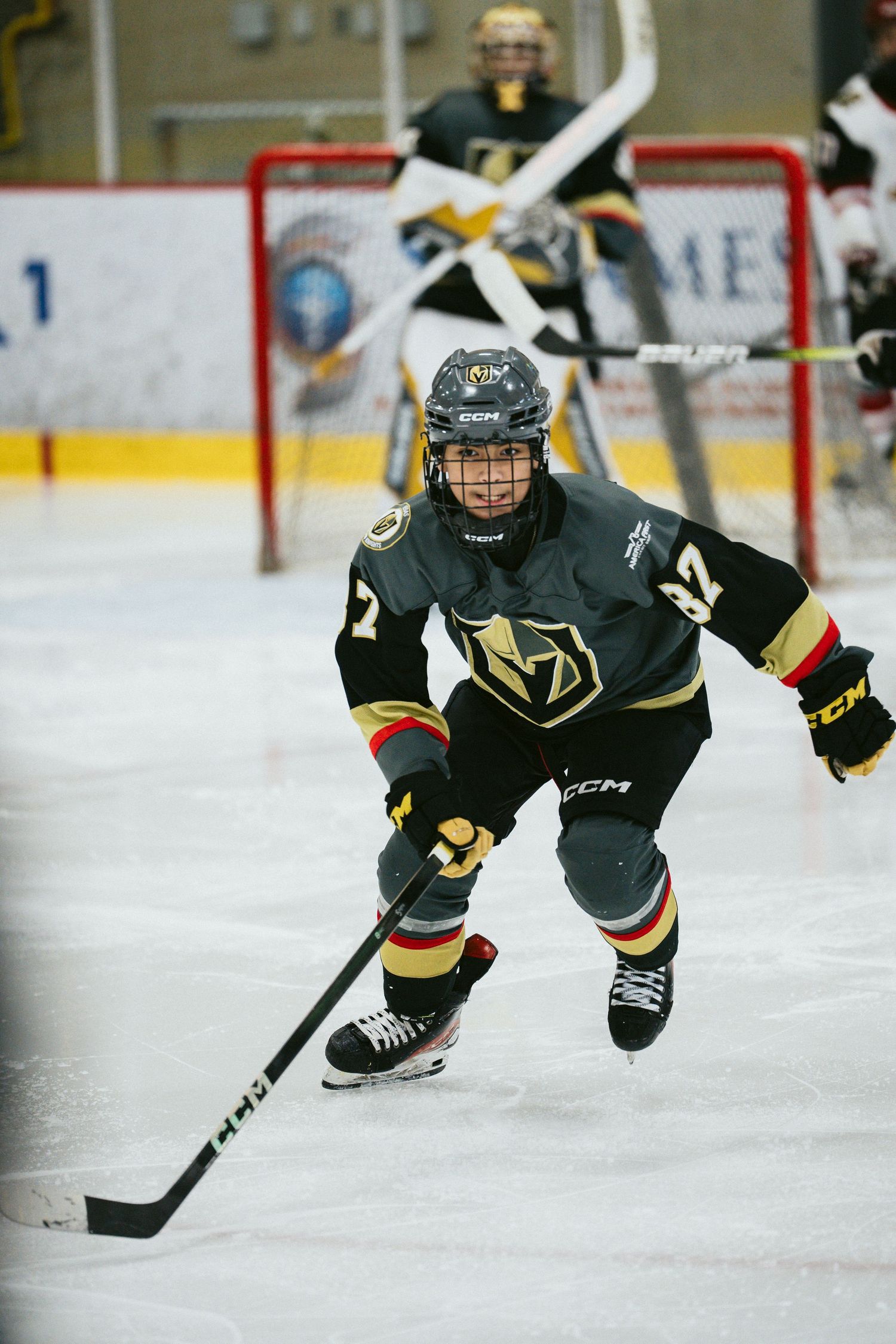 Hockey players in black and gold uniforms dive low to the ice during practice drills.