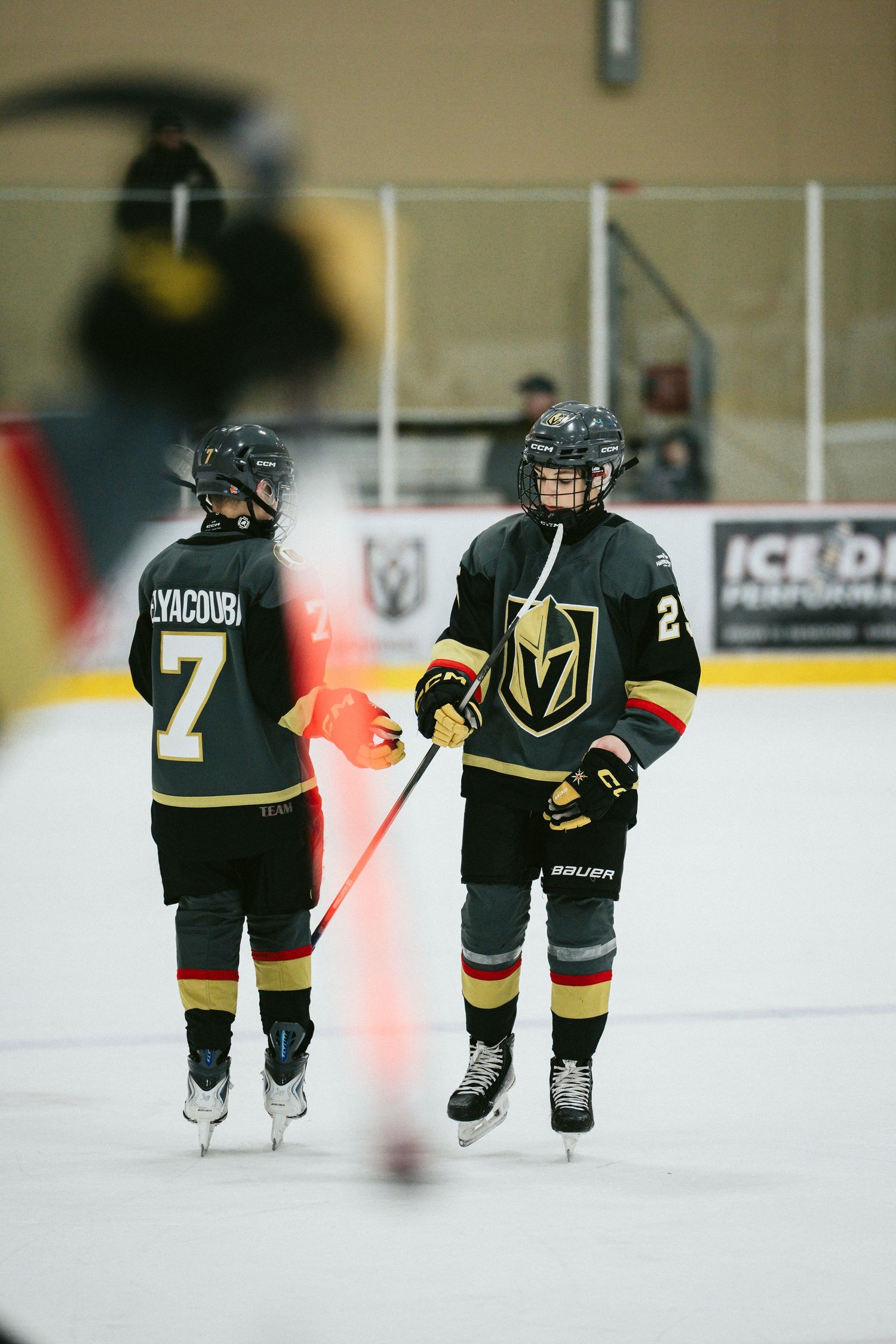 Youth hockey players in black and gold uniforms skating on ice during practice.