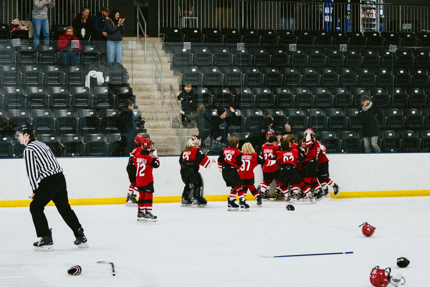 Youth hockey players spread across indoor ice rink during practice.