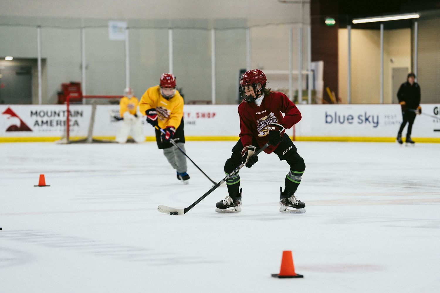 Two youth hockey players practice skating drills on an indoor ice rink during a hockey training camp.