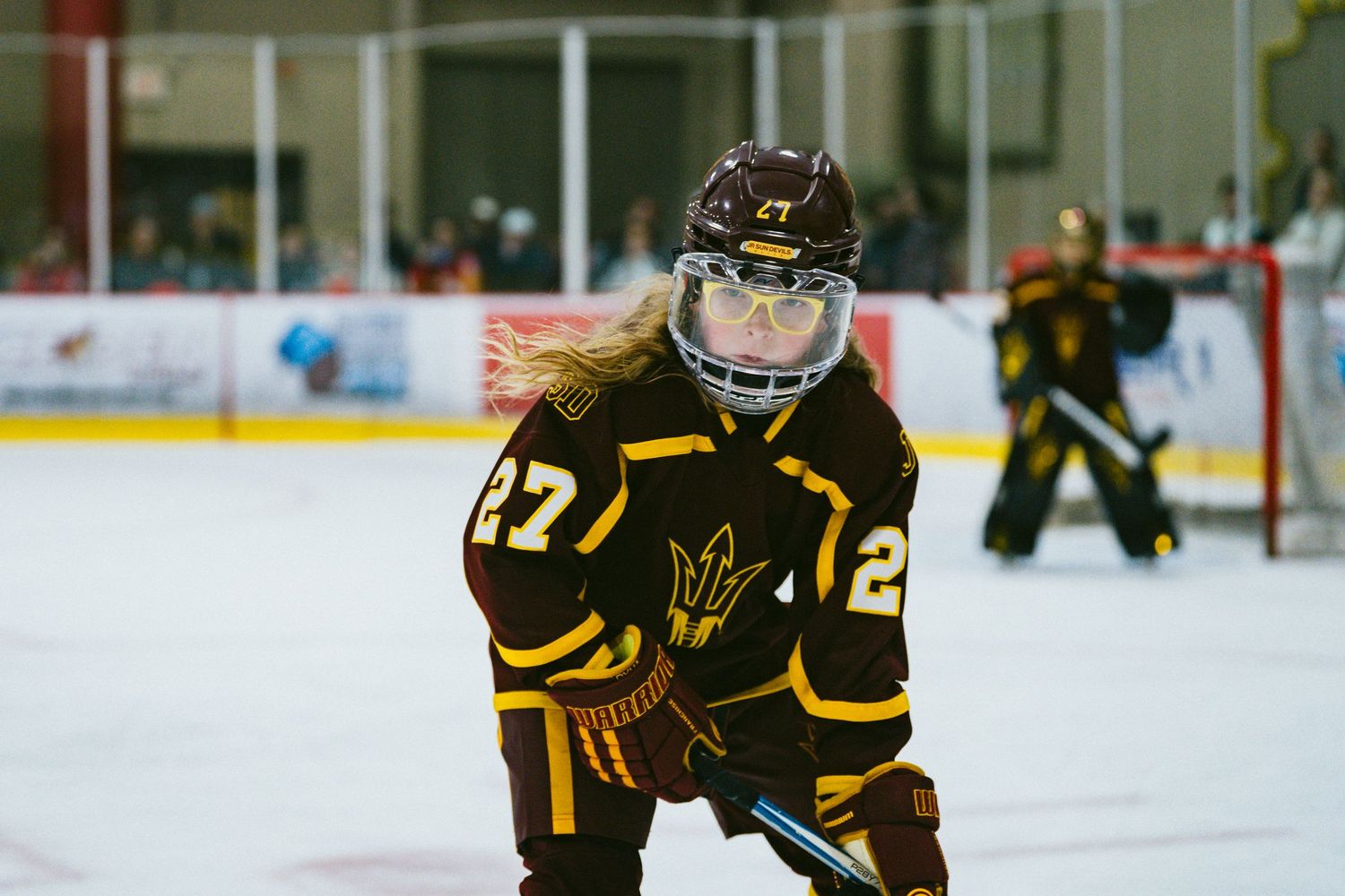 Youth hockey players in black and gold jerseys skating in formation during a match.
