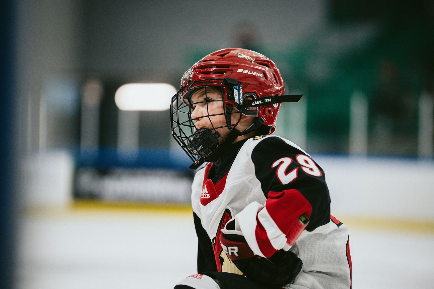 Youth hockey player in red and black uniform skating during game.
