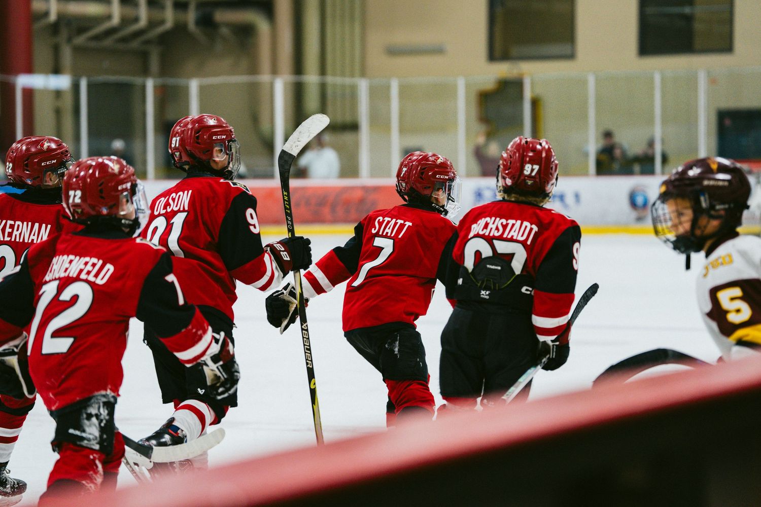 Red team players line up along the boards during an ice hockey game.