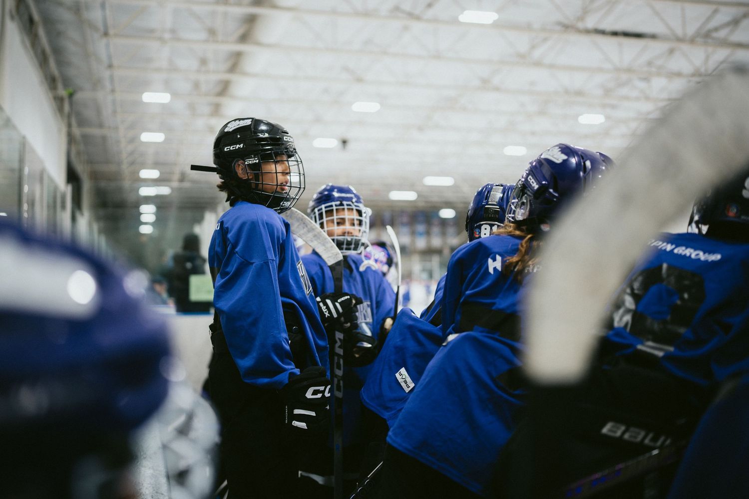 Youth hockey team in blue jerseys huddles together for a pep talk during ice hockey game.