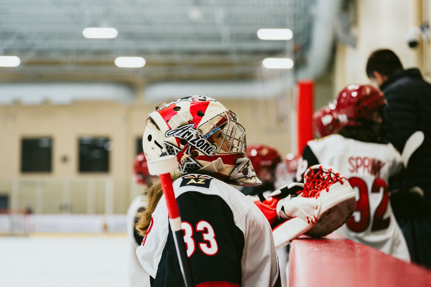 Ice hockey players in red and white jerseys gather on the rink during a competitive match.