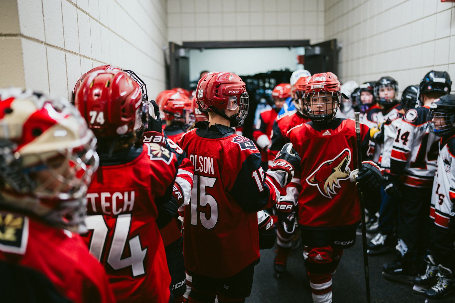 Hockey players in red jerseys gather in a hallway before a game.