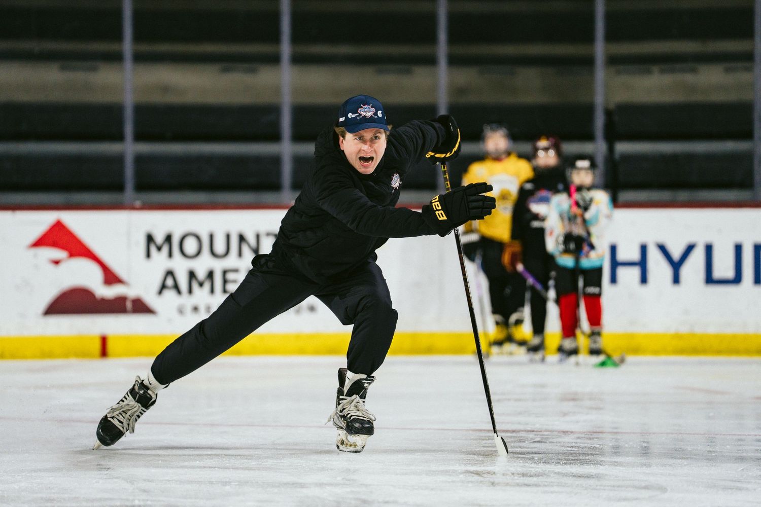 Hockey player performs wide skating stride drill on ice rink during youth hockey training session.