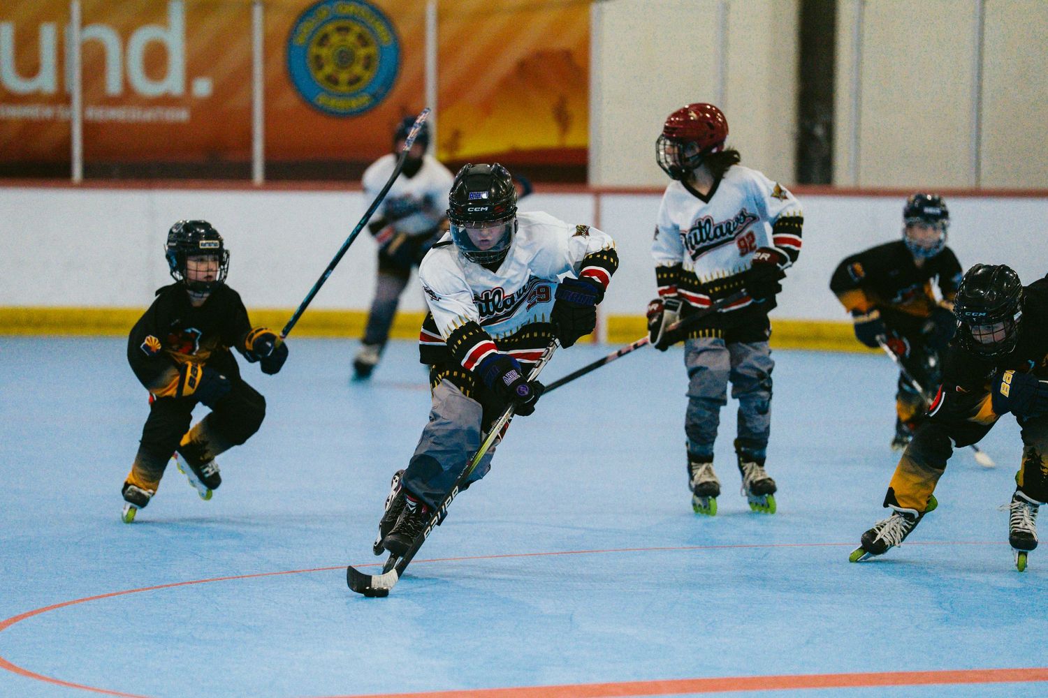 Group of young inline roller hockey players compete during a fast-paced indoor youth hockey game.