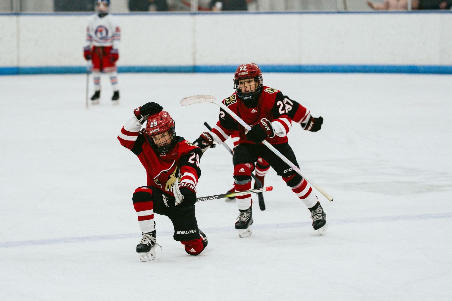 Young hockey players dive and slide across the ice while pursuing the puck.