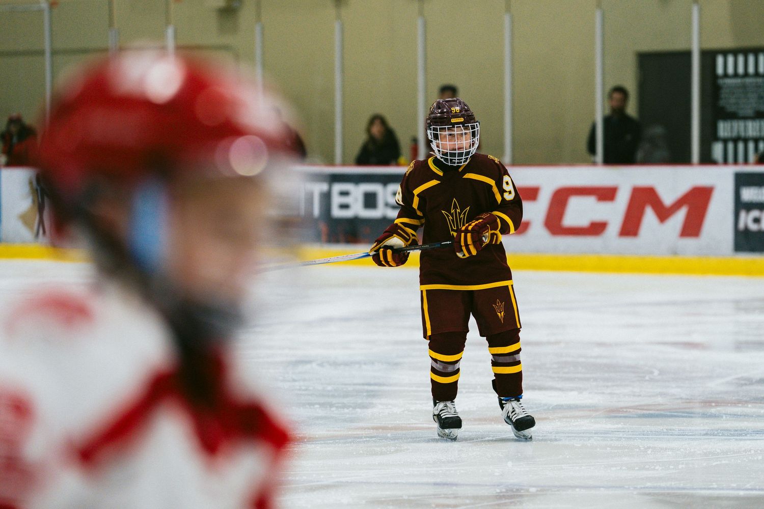 Hockey players from opposing teams face off on the ice with arena signage visible in background.