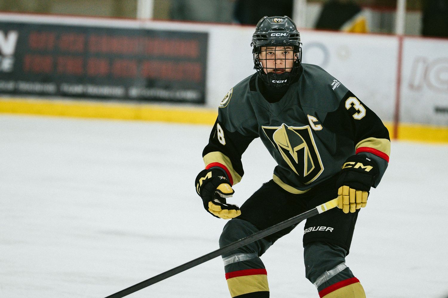 Hockey players in dark jerseys position themselves during gameplay on the ice rink.