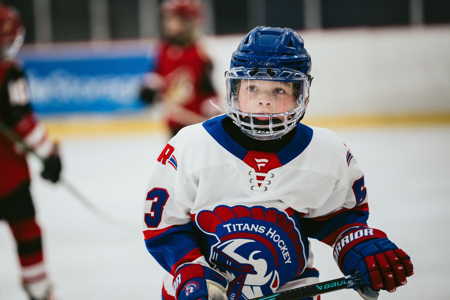 Players in red and blue uniforms skate across the ice during a competitive hockey match.