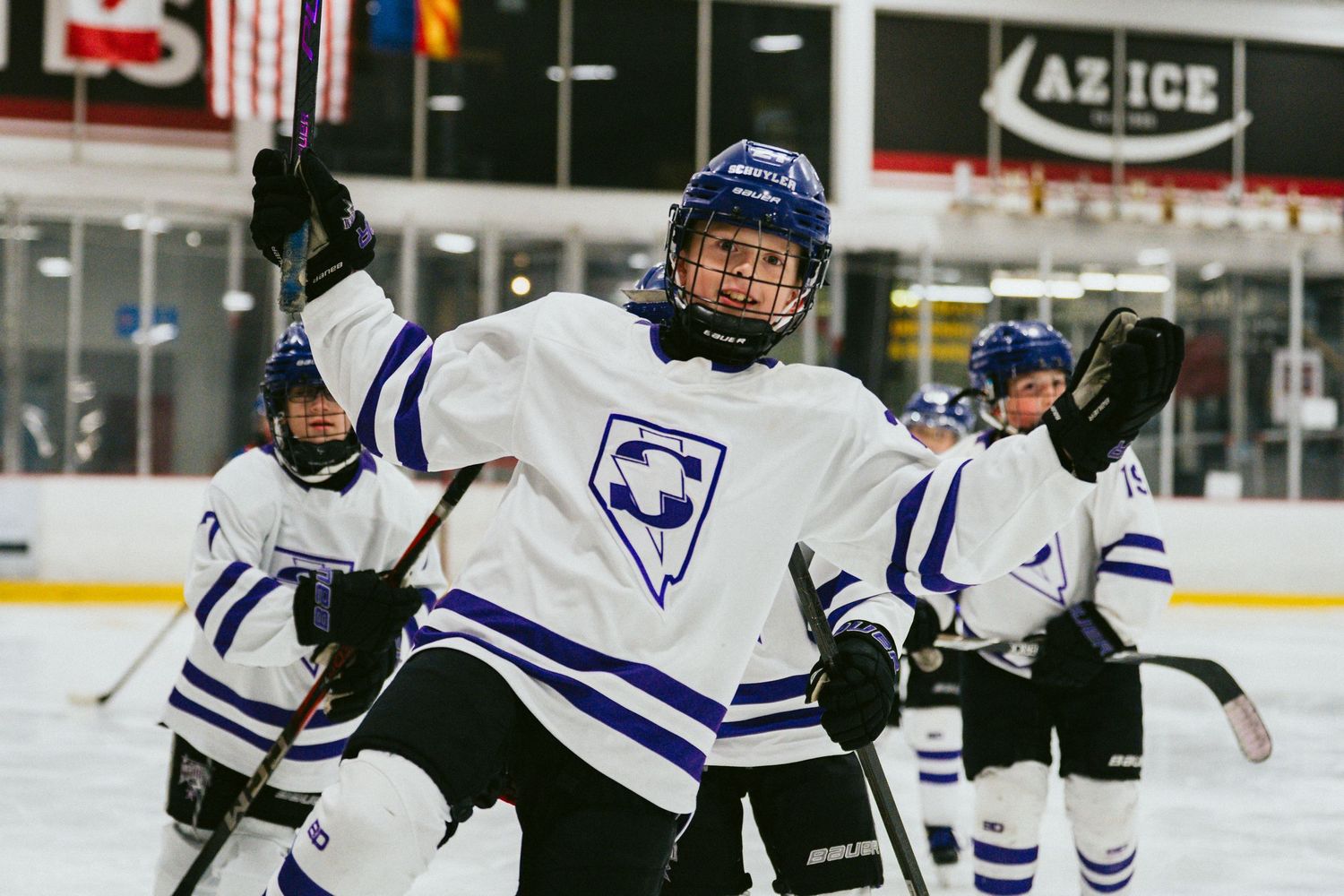 Hockey players in blue and white uniforms celebrate during an ice hockey match.