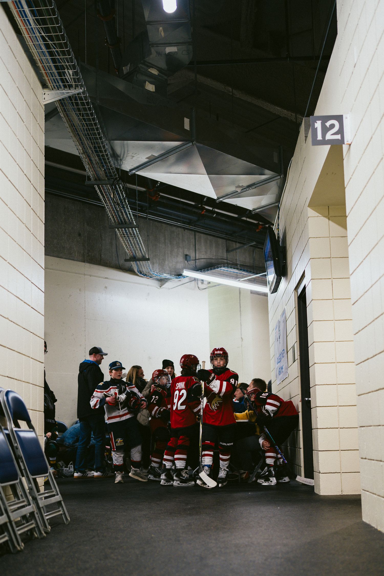 Hockey team gathered in arena hallway wearing red and white jerseys.