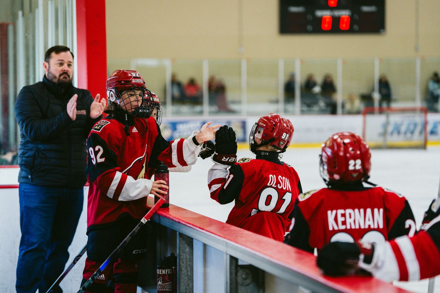 Hockey players in red jerseys compete for the puck during an intense ice hockey match.