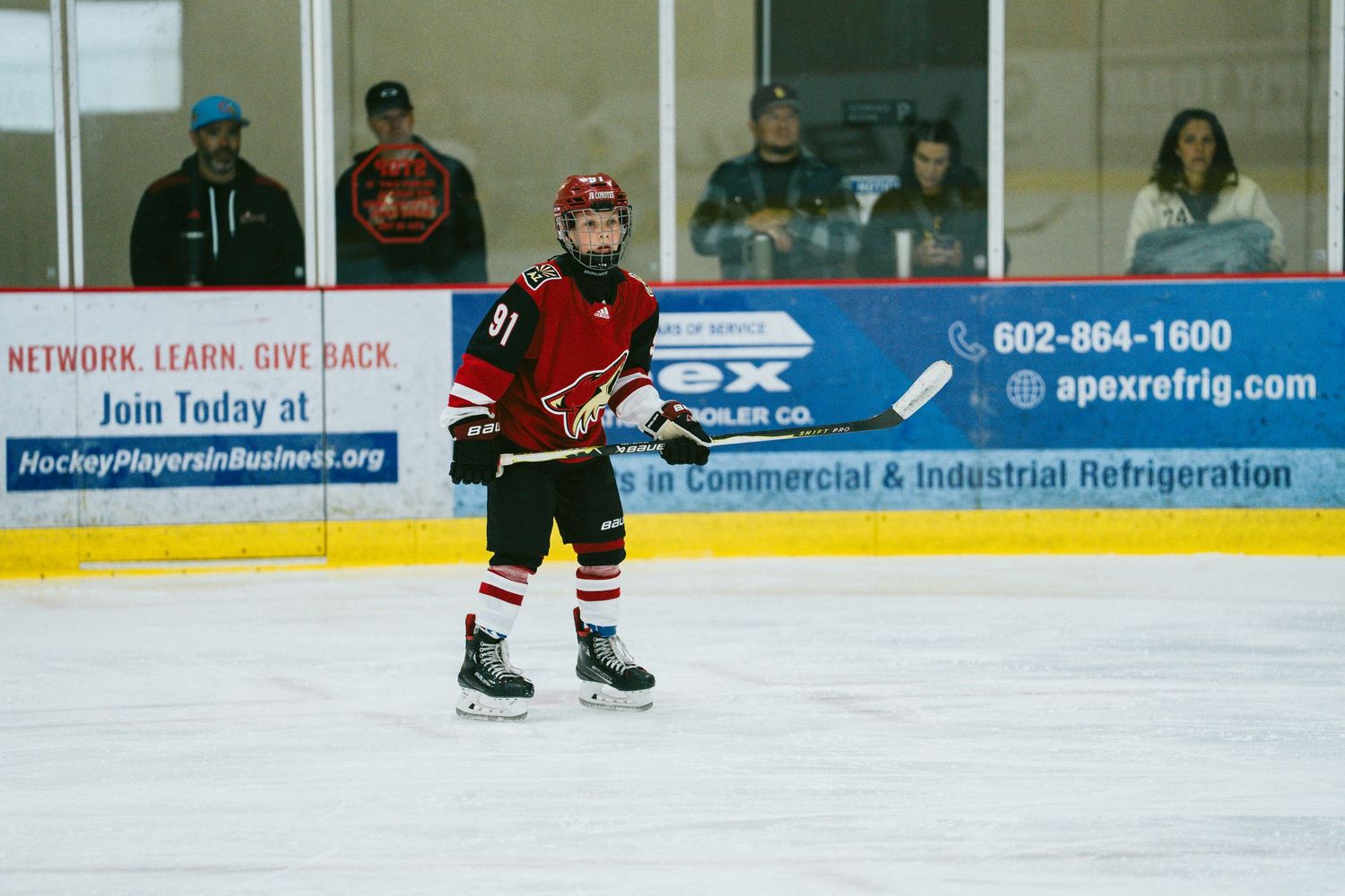 Empty hockey rink boards displaying various advertisements and contact information during a game.