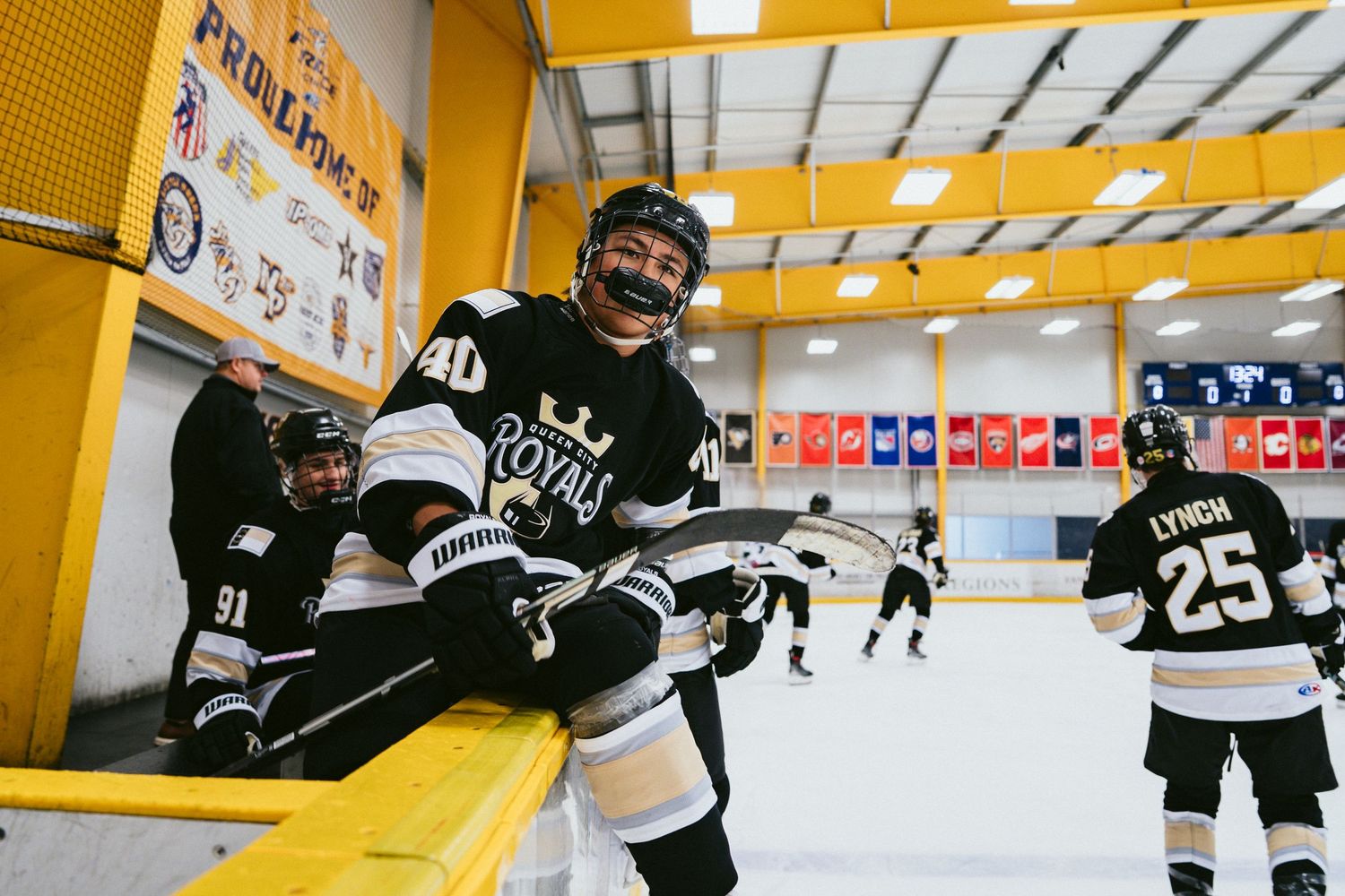 Hockey player in Royals jersey smiling on the bench during an indoor ice hockey game.