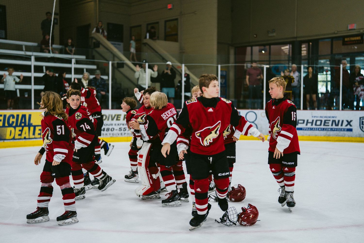 Hockey team in red uniforms practicing formations and drills on the ice rink.