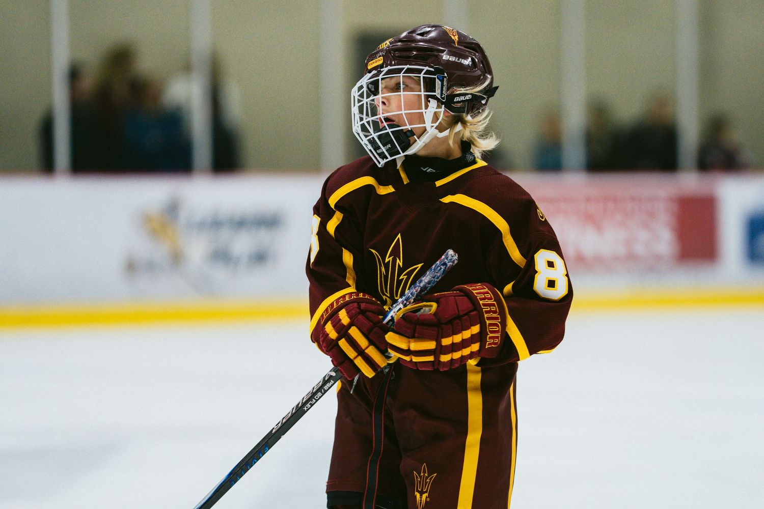 Hockey players in protective gear skate across ice rink during competitive match.