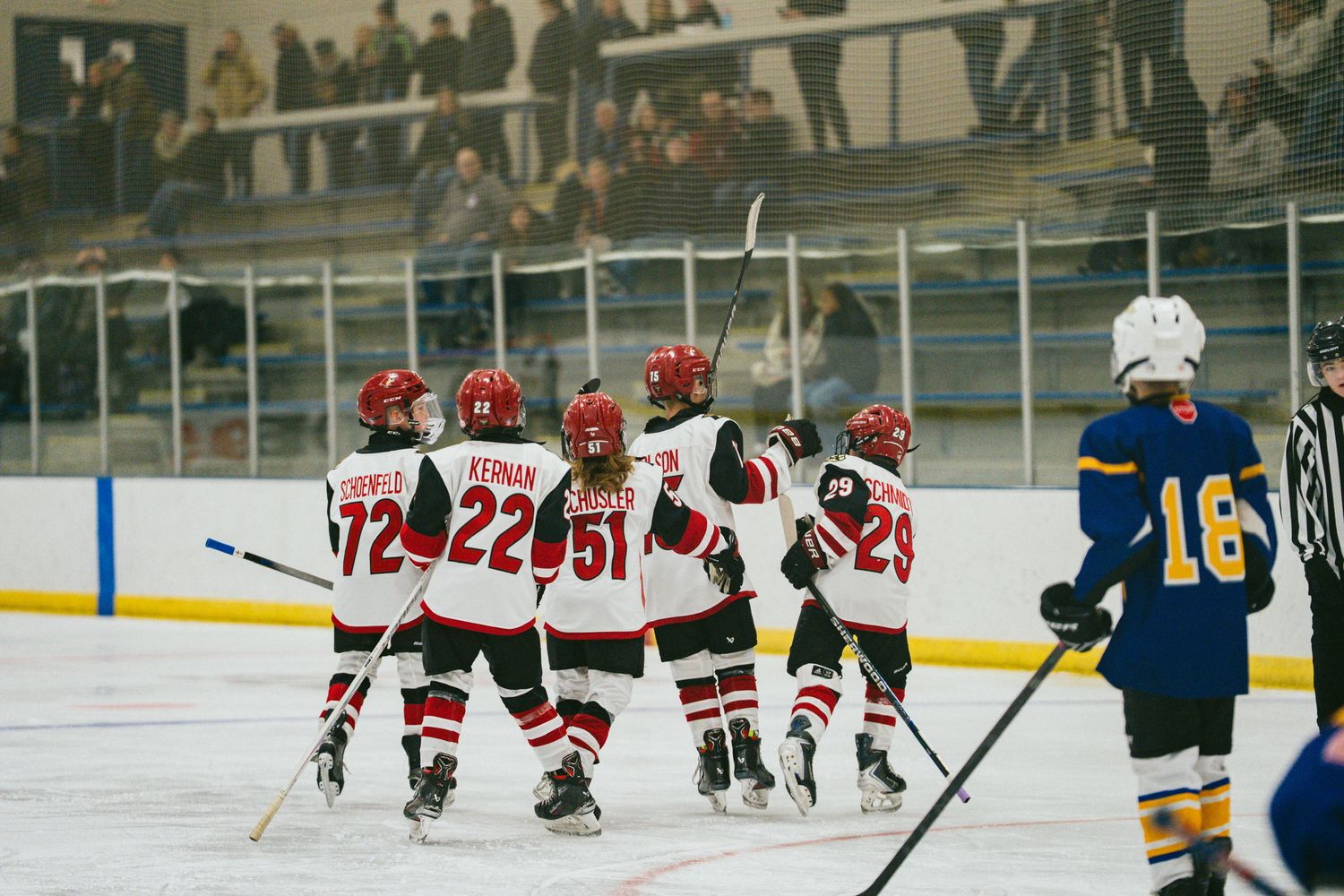 Hockey players spread across the ice during a game with spectators watching from the sidelines.