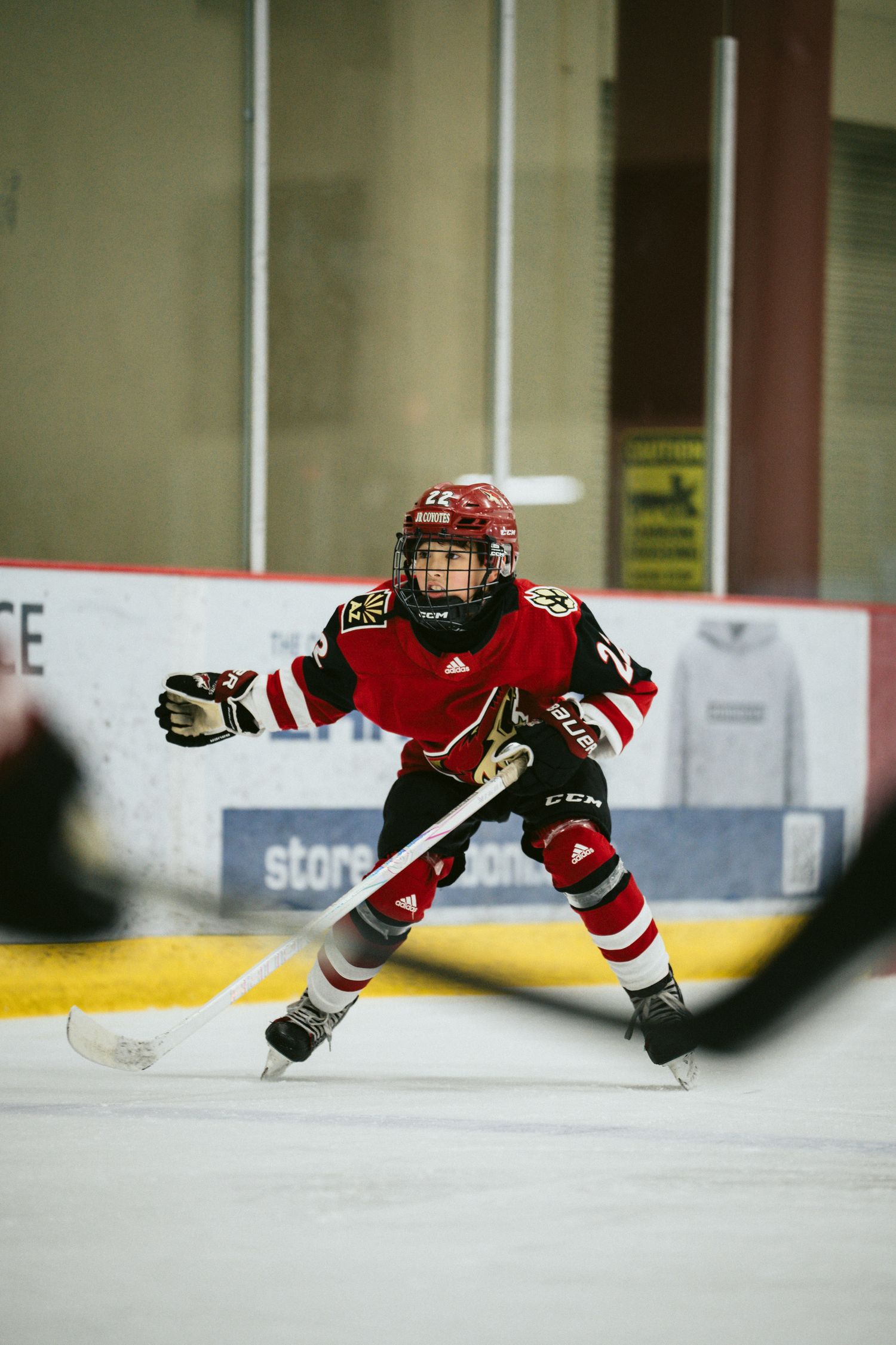 Hockey player in red uniform gliding low on ice during game action.