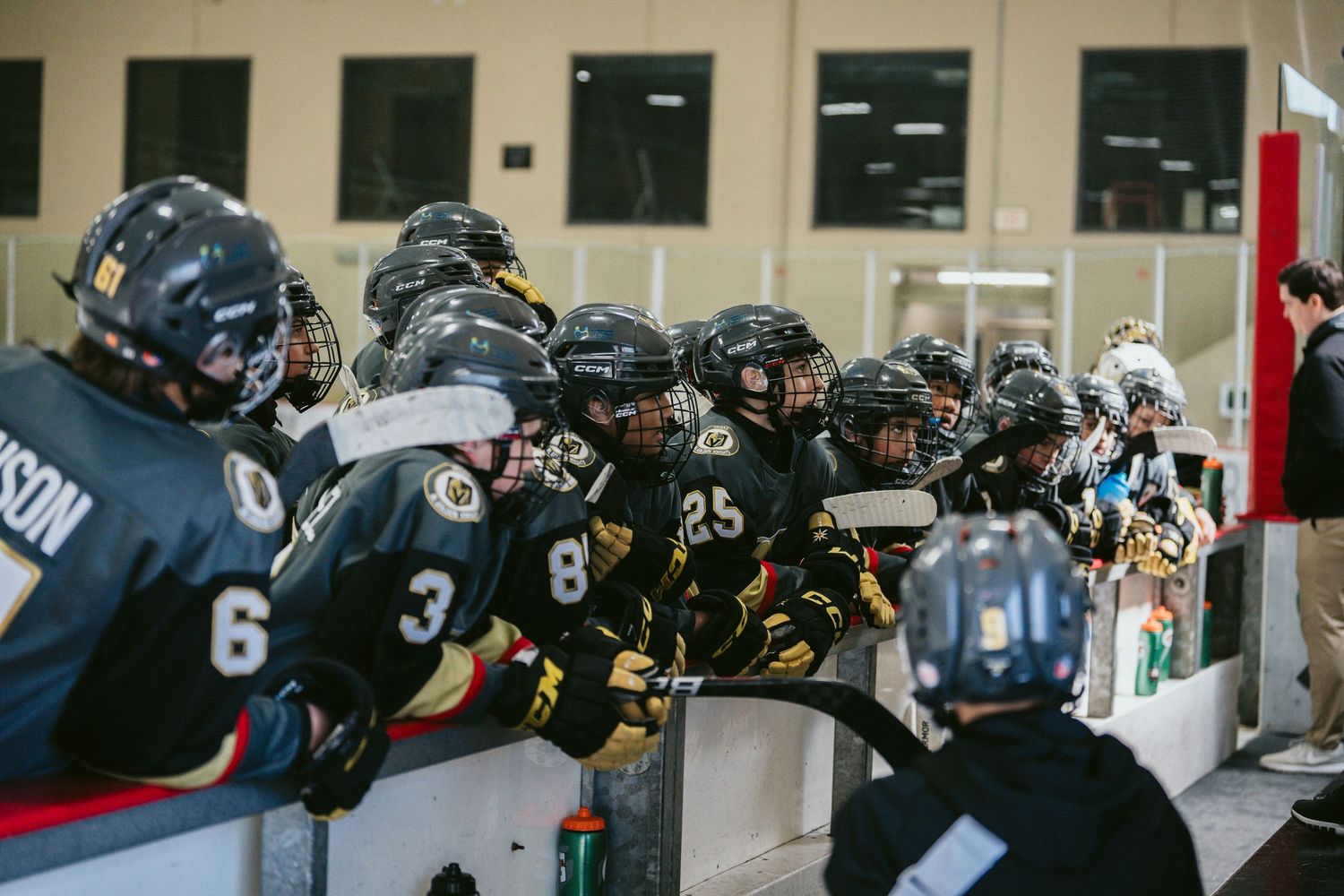 Hockey players in black jerseys gathered along the boards during a game.