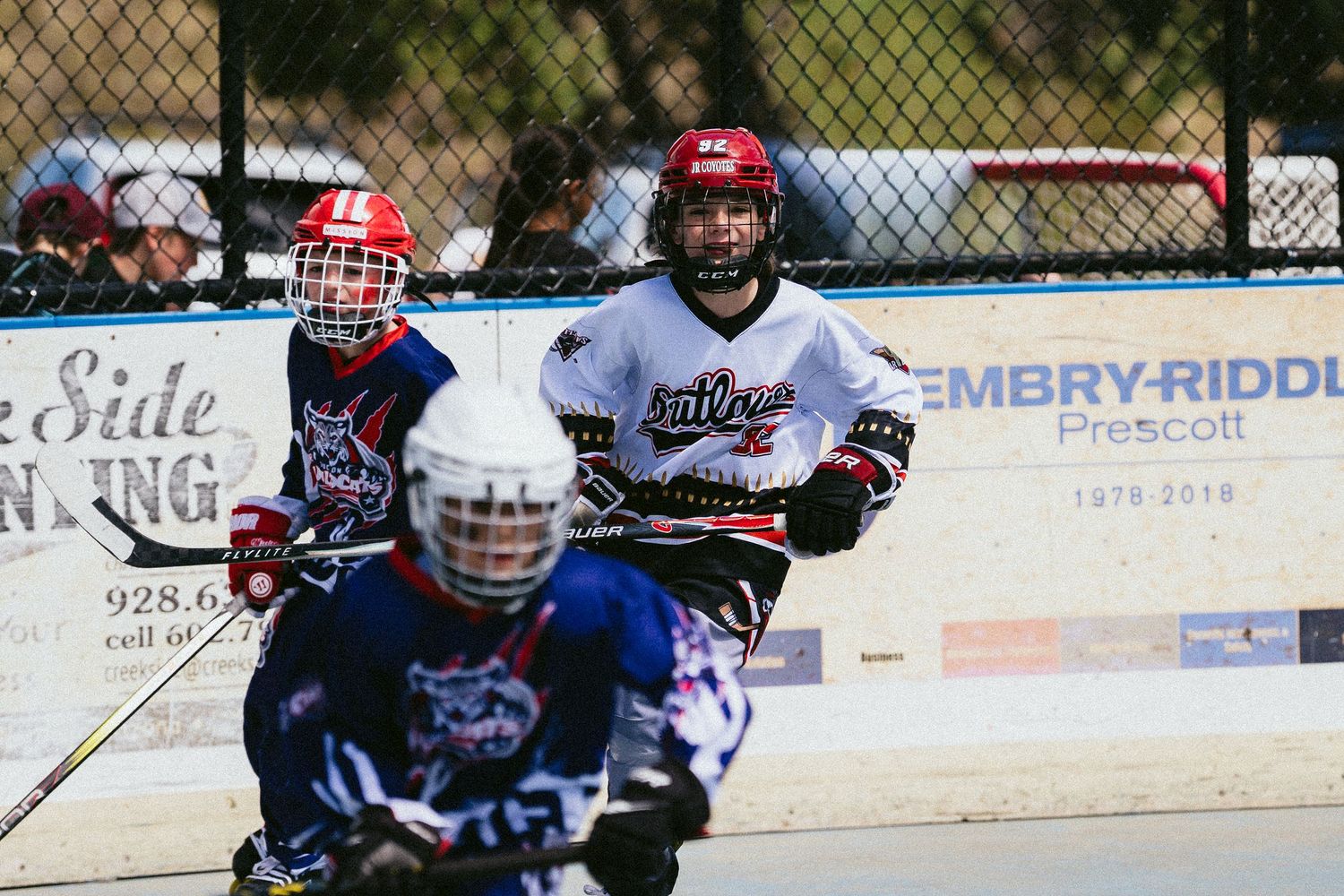 Youth inline hockey players compete on an outdoor rink near Embry-Riddle Prescott in full protective gear.