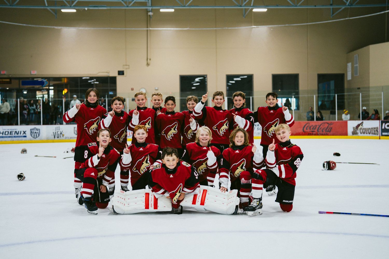Youth hockey team in red jerseys poses together on the ice rink for a group photo.