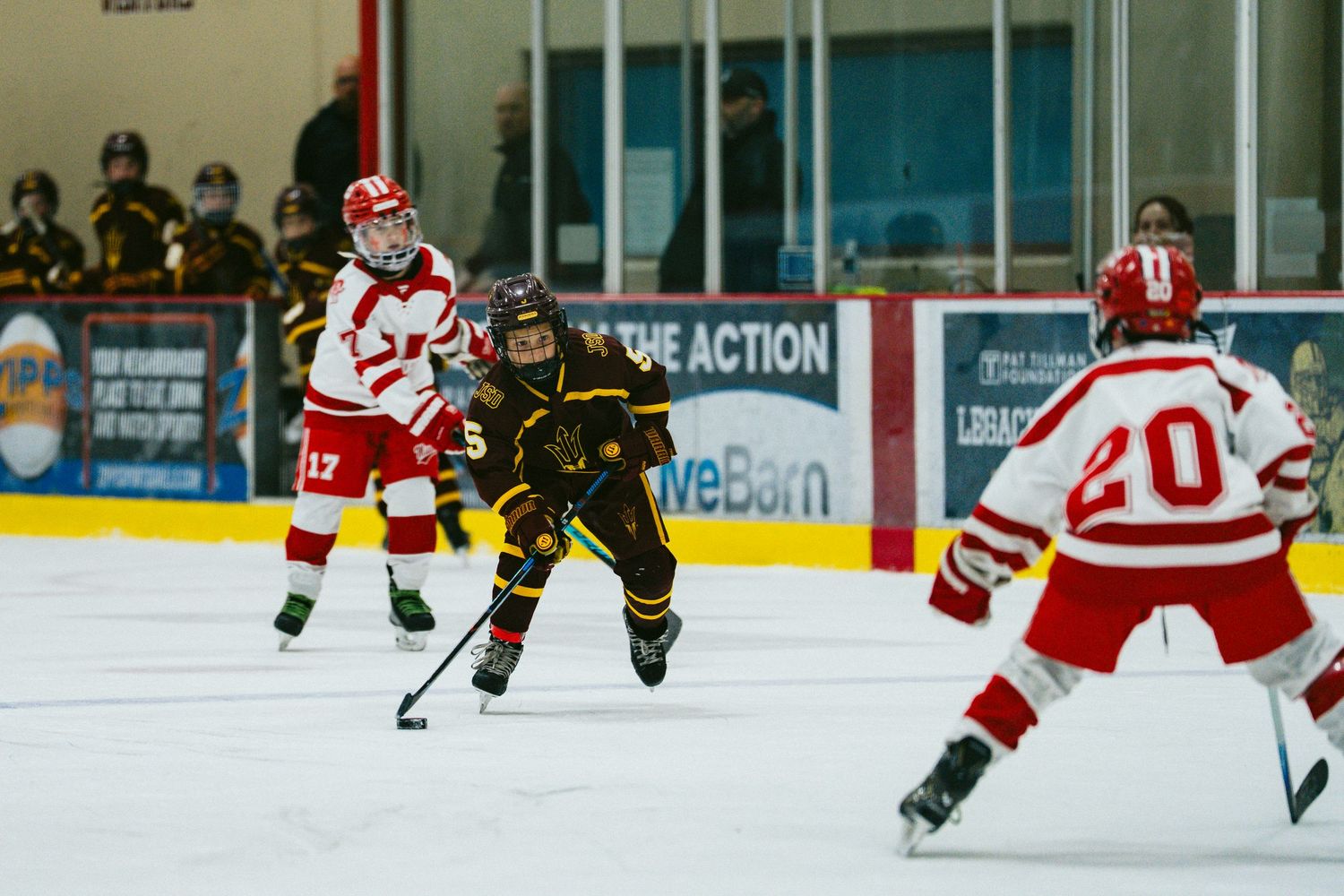 Hockey players in red and black uniforms compete for the puck during an intense ice hockey match.